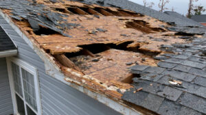 Severely damaged roof with large holes and missing shingles.